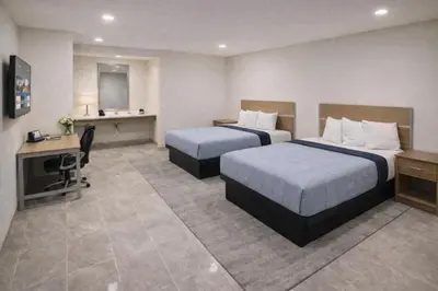 a hotel room with two beds and a desk at Super 8 by Wyndham Bakersfield CA in Bakersfield