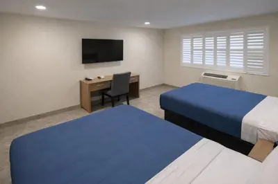 a hotel room with two beds and a desk and a television at Super 8 by Wyndham Bakersfield CA in Bakersfield