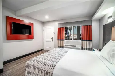 a bedroom with a bed and a flat screen tv at Rodeway Inn South Gate - Los Angeles South in South Gate