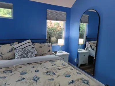 a blue bedroom with a bed and a mirror at Hill Street Cottage in Los Angeles