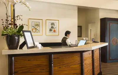 a man sitting at a desk with two laptops at Ayres Hotel Orange in Anaheim