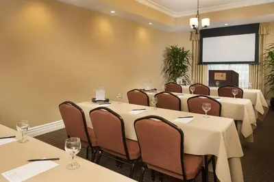 a conference room with tables and chairs and a screen at Ayres Hotel Orange in Anaheim