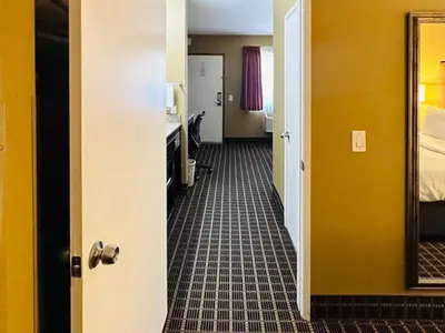 a hallway of a hotel room with a bed and a mirror at Quality Inn & Suites Westminster Seal Beach in Westminster