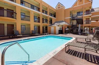 a pool in front of a apartment building with chairs at Quality Inn & Suites Westminster Seal Beach in Westminster