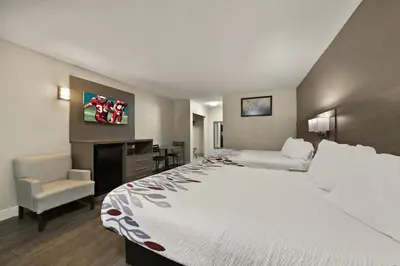 a hotel room with a large bed and a chair at Red Roof Inn Los Angeles - Bellflower in Bellflower