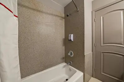 a bathroom with a white bath tub and a door at Red Roof Inn Los Angeles - Bellflower in Bellflower