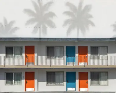 a building with orange and blue doors and palm trees at The Sojourn Los Angeles - Sherman Oaks in Sherman Oaks