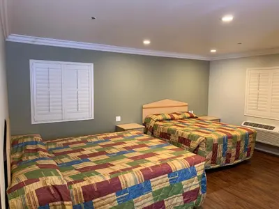 a bedroom with two beds and two windows at El Rey Inn - LAX in Gardena