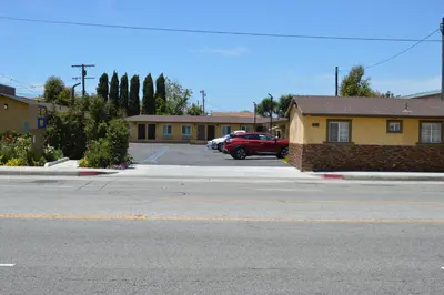 a parking lot with a red car parked in front of a house at El Rey Inn - LAX in Gardena