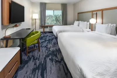 a hotel room with two beds and a desk and a television at Fairfield Inn & Suites by Marriott Moorpark Ventura County in Moorpark