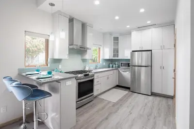 a kitchen with white cabinets and stainless steel appliances at Mid-Mod Retro Private Studio & Pool in Long Beach