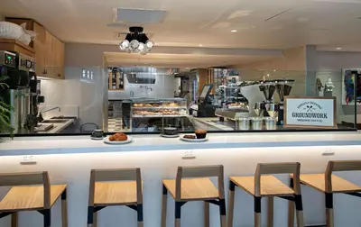 a restaurant with a counter with chairs and a kitchen at The Wayfarer Downtown LA, Tapestry Collection by Hilton in Los Angeles