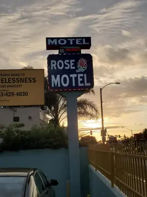 a motel sign in front of a road with a car at Rose motel in Compton