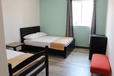 a small room with two beds and a red chair at 8th and Ardmore in Los Angeles
