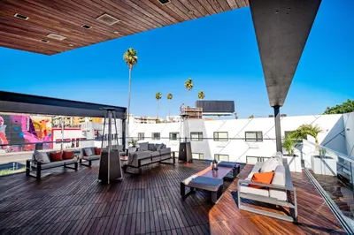 a rooftop deck with chairs and tables on a building at The Moment Hotel in Los Angeles