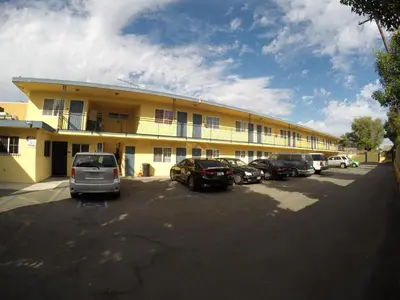 a large yellow building with cars parked in a parking lot at Calico Motel in Anaheim