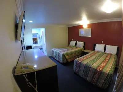 a hotel room with two beds and a desk at Calico Motel in Anaheim