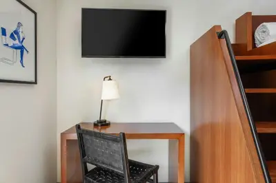 a desk with a chair and a television on a wall at FOUND Hotels, Santa Monica, Series by Marriott in Los Angeles
