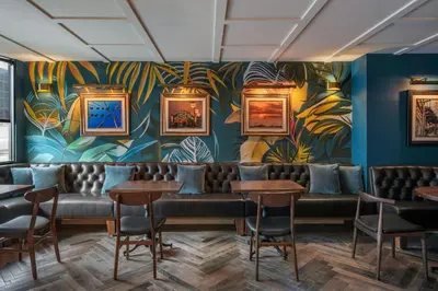 a room with chairs and a wall with a mural at FOUND Hotels, Santa Monica, Series by Marriott in Los Angeles