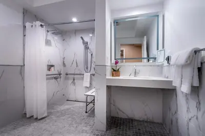 a white bathroom with a sink and a mirror at Beverly Hills Plaza Hotel & Spa in Los Angeles