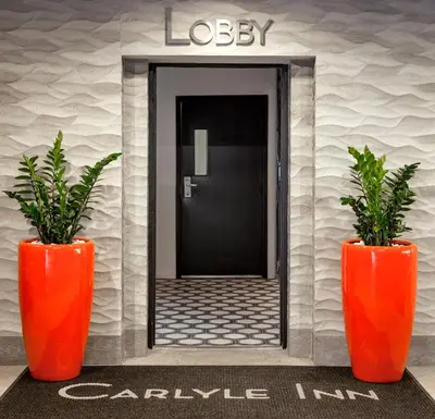 two orange vases with plants in front of a lobby at Carlyle Inn in Los Angeles