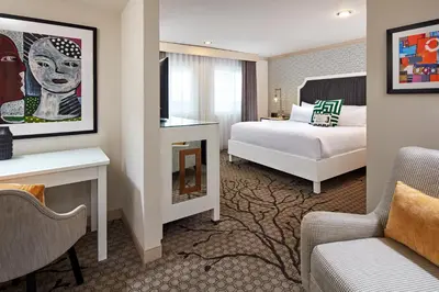 a hotel room with a bedroom with a bed and a desk at Carlyle Inn in Los Angeles