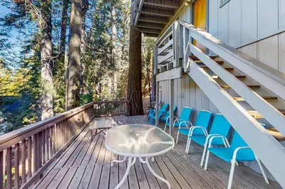 a deck with chairs and a table and stairs at The Treehouse in Lake Arrowhead