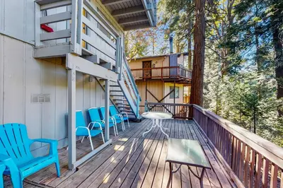 a deck with blue chairs and a staircase on a house at The Treehouse in Lake Arrowhead