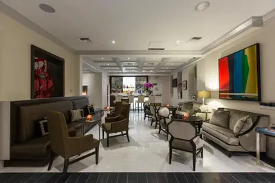 a lobby with chairs and tables and a colorful painting at Mosaic Hotel Beverly Hills in Los Angeles