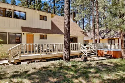 a house with a deck and a tree in front of it at All Season Alpine Retreat-1184 by Big Bear Vacations in Big Bear Lake