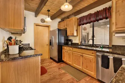 a kitchen with wooden cabinets and a stainless steel refrigerator at All Season Alpine Retreat-1184 by Big Bear Vacations in Big Bear Lake