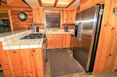 a kitchen with wooden cabinets and a stainless steel refrigerator at Knotty and Nice-177 by Big Bear Vacations in Big Bear Lake
