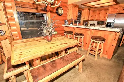 a kitchen with a wooden table and some stools at Knotty and Nice-177 by Big Bear Vacations in Big Bear Lake
