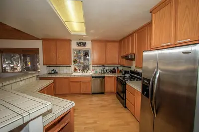 a kitchen with wooden cabinets and a stainless steel refrigerator at Can't Bear to Leave-1156 by Big Bear Vacations in Big Bear Lake