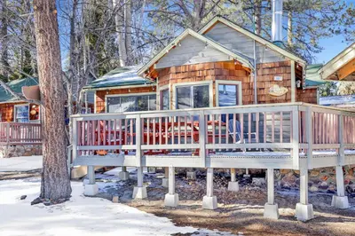 a log cabin with a large deck in the snow at Shore Acres Lodge-450 by Big Bear Vacations in Big Bear Lake