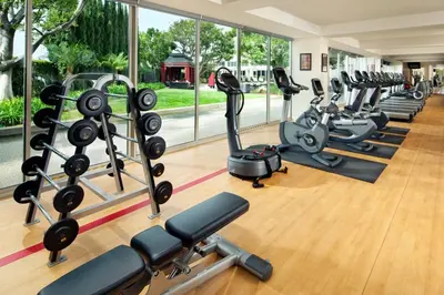 a gym with rows of treadmills and elliptical machines at Sheraton Gateway Los Angeles Hotel in Los Angeles