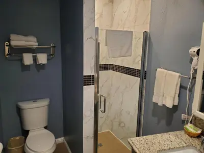 a bathroom with a shower with a toilet and a sink at Ocean Surf Inn & Suites in Huntington Beach