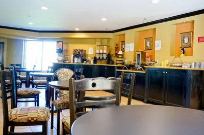 a restaurant with tables and chairs and a bar at Ramada by Wyndham Ontario Airport & Convention Center in Ontario