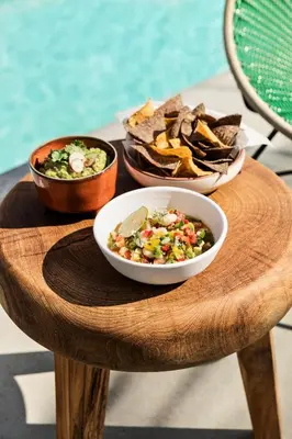 a wooden table with bowls of food and chips at Hotel June West LA, a Member of Design Hotels in Los Angeles