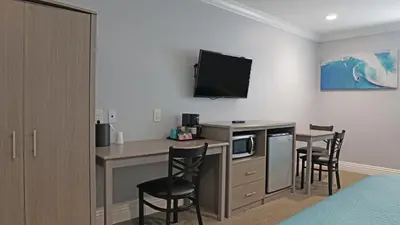 a hotel room with a kitchen and a desk with chairs at Surf City Inn in Huntington Beach