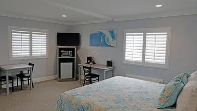 a bedroom with a bed and a table and a desk at Surf City Inn in Huntington Beach