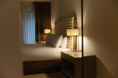 a bedroom with a bed with two lamps and a mirror at Luxe Sunset Boulevard Hotel in Los Angeles