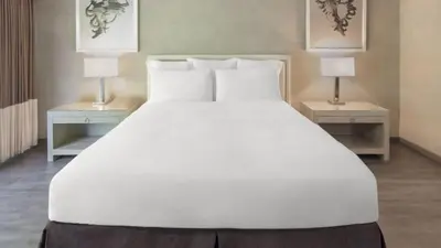 a large white bed with two tables and two lamps at Luxe Sunset Boulevard Hotel in Los Angeles
