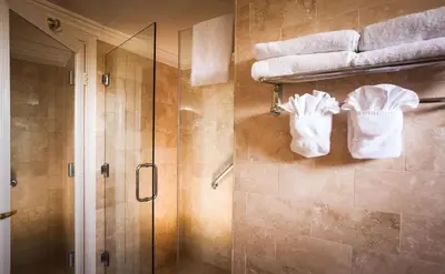 a bathroom with a shower and towels on a wall at Best Western Plus Sunset Plaza Hotel in Los Angeles