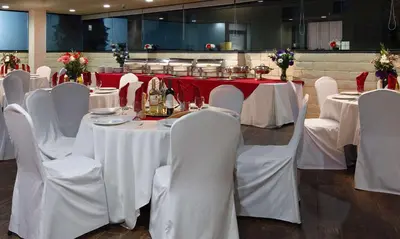 a dining room with white tables and white chairs at Coast Burbank Hotel in Burbank