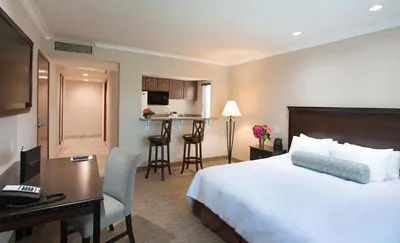 a hotel room with a bed and a desk and a kitchen at Coast Burbank Hotel in Burbank