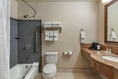 a bathroom with a toilet and a sink and a tub at Citrus Suites Redlands Loma Linda Hotel in Redlands