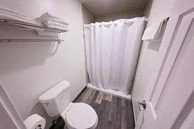 a white bathroom with a toilet and a shower at GAREY MOTEL in Pomona