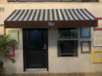 a shop with a black door and a striped awning at L.A. Sky Boutique Hotel in Los Angeles