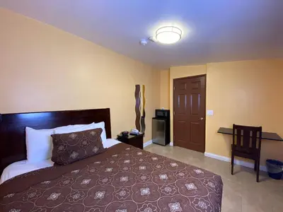 a bedroom with a bed and a table and a door at El Patio Inn - Near Universal Studios Hollywood in Los Angeles